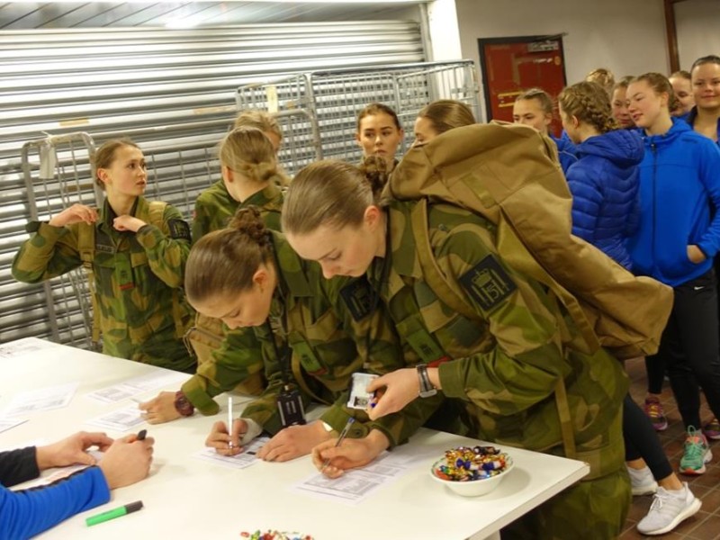 Kvinner i kø for å få utlevert formsydde paradeuniformer. Rikke Heggedal skimtes midt i gjengen.