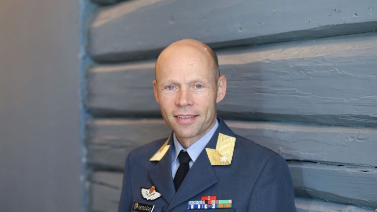 Mann i uniform foran blå vegg