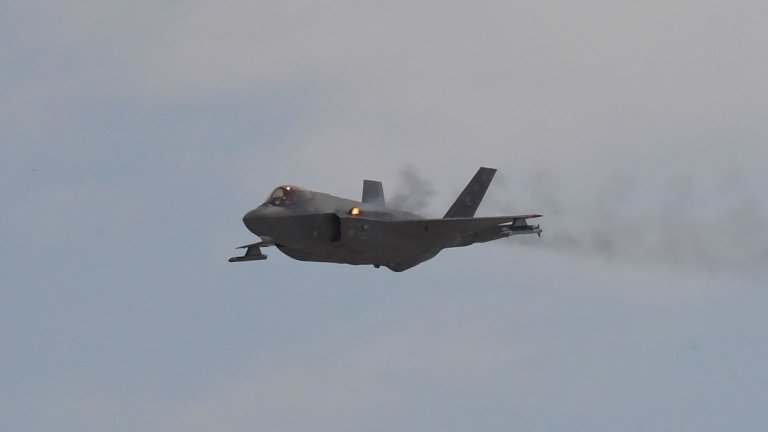 Et F-35-kampfly skyter med kanon, vi ser munningsflamme fra den ene vingen.