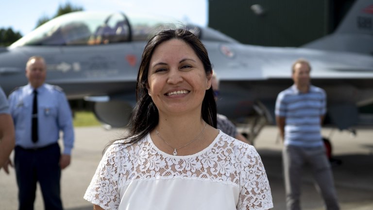 Smilende kvinne foran et jagerfly